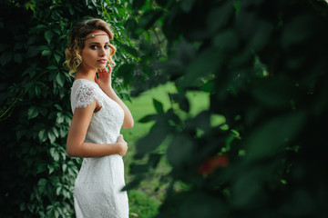 Elegant lady stands in a white lace dress between the walls of g