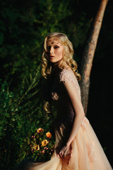 Stunning blonde looks over her shoulder standing in a long beig