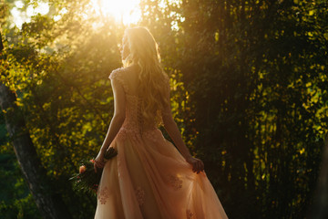 Sun shines through the delicate beig dress  put on a tender blon