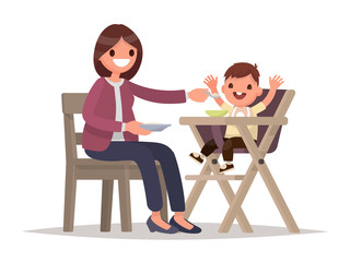 Child Feeding. Mother feeds the baby sitting in the highchair. V