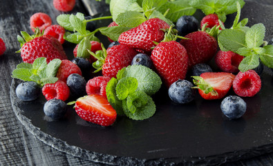 fresh strawberries, raspberries and blueberries on a black background