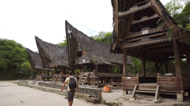 Backpacker male traveler walking around traditional batak village on Sumatra