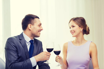 young couple with glasses of wine at restaurant