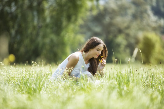 Woman crouching on a meadow smelling flowers