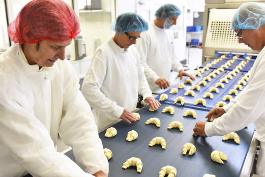 Workers at production line in a baking factory with croissants