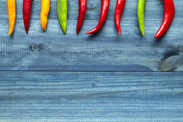 Colorful cayenne chili peppers on blue wooden table.