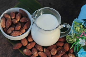 Almond milk with almond on wood background.