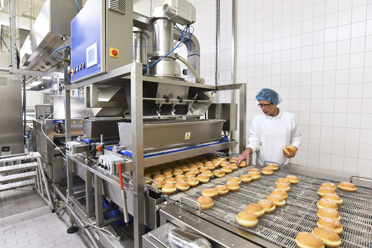 Worker at production line in a baking factory with Berliners