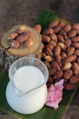 Almond milk with almond on wood background.