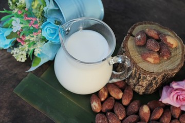 Almond milk with almond on wood background.