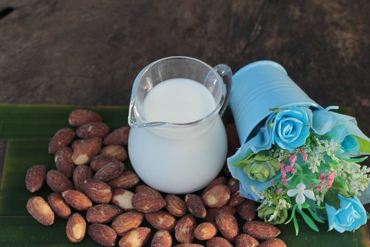 Almond milk with almond on wood background.