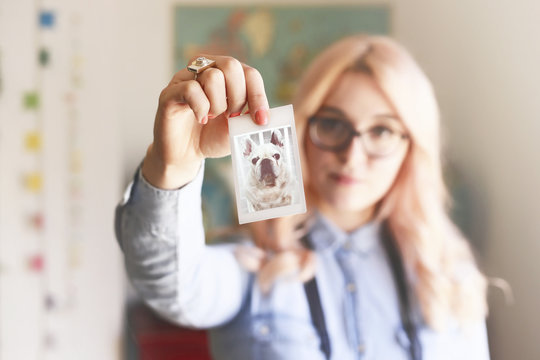 Young woman holding a polaroid of French bulldog