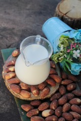 Almond milk with almond on wood background.