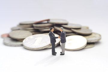 Business handshake and business people over money background , miniature people business man concept