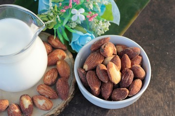 Almond milk with almond on wood background.