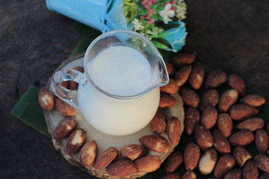 Almond milk with almond on wood background.