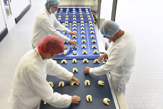Workers at production line in a baking factory with croissants