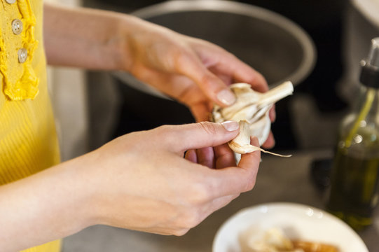Woman in kitchen holding garlic