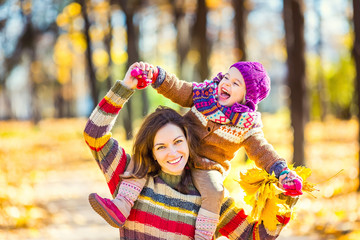 Little girl playing with mother in the autumn park