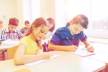 group of school kids writing test in classroom