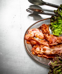 Fried bacon with greens. On Metal table.