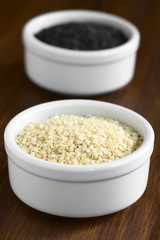 White and black sesame seeds in small bowls, photographed with natural light (Selective Focus, Focus one third into the white seeds)