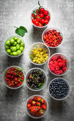 Fresh forest berries in the glasses. On stone table.