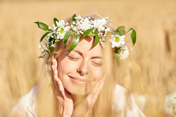 happy woman in wreath of flowers on cereal field