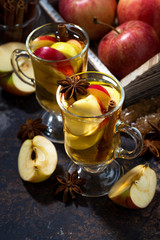 glasses of hot apple tea with spices on dark table, vertical 