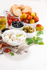 ingredients for salad with mozzarella on white table, vertical