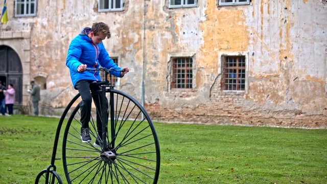 Boy sit on big front wheel bicycle