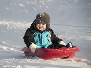 Fototapeta na wymiar Child sledding in winter