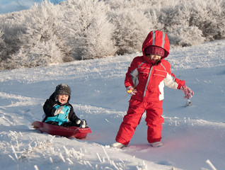 Two children sledding in winter