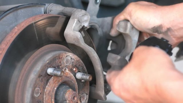 Technician or Mechanic is replacing disc brakes of car. Car maintenance and service.