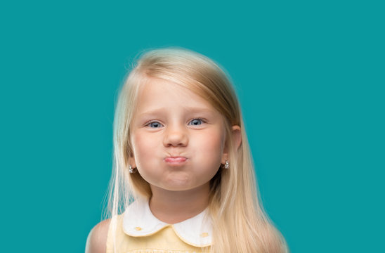 Small, young, funny girl, inflated cheeks on 
cyan background

