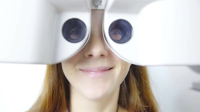 Woman look through optometry Phoropter and smile 4K