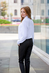 Beautiful brown-haired young woman wearing clothes and walking o