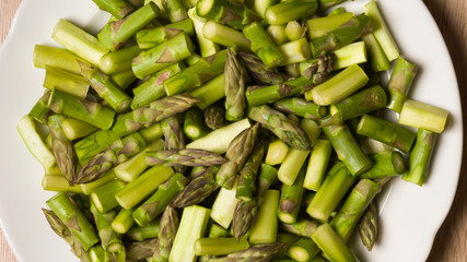 Close up on sliced pieces of green asparagus on a white plate