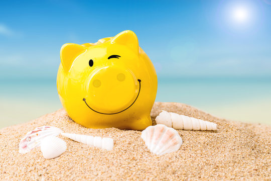 summer happy piggy bank on white sand beach with blue sea on day noon light.
