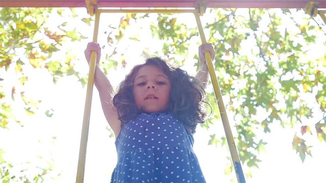 Slow motion of a cute little girl swinging, sun flare