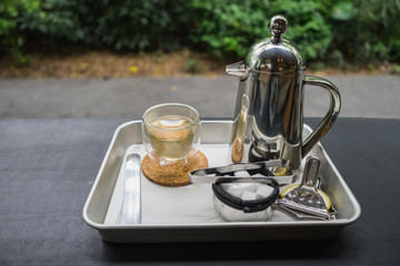 hot fresh tea in see through glass and silver shinning tea pot with silver spoon on black table at coffee time / hot fresh tea