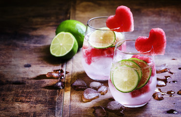 Refreshing drink with watermelon, soda and lime, dark wooden bac