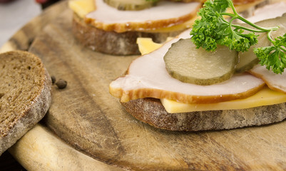 Sandwich with meat and chease on cutting board. Soft focus