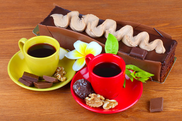 chocolate cake with two cup of coffee and chocolate balls on wooden table
