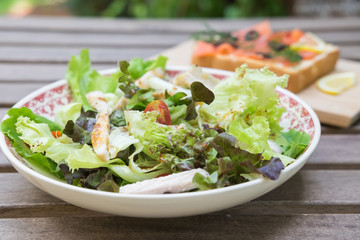 Chicken and vegetable salad on the wooden table in the garden