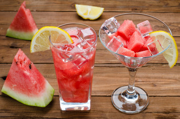 Watermelon dessert with ice cubes on brown wooden table.