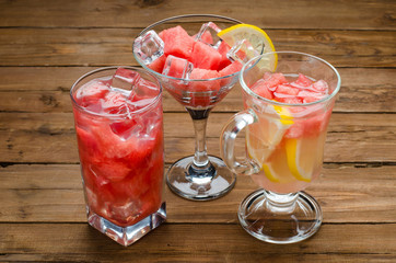 Fresh watermelon cocktail with lemon and ice cubes on a wooden t