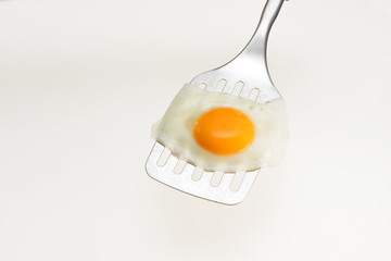 Fried egg on the spatula, ready to be served. White background.