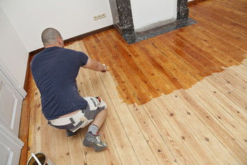 homme mettant huile de protection sur plancher au rouleau