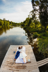 Bride and groom lying on a wooden pier near the pond 